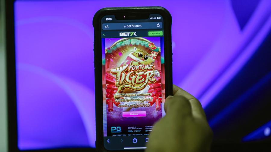 homem-segura-celular-mostrando-o-jogo-fortune-tiger-conhecido-como-jogo-do-tigrinho-1727451874143_v2_900x506